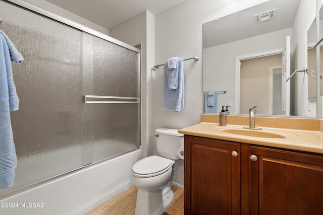 bathroom with visible vents, toilet, combined bath / shower with glass door, vanity, and wood finished floors