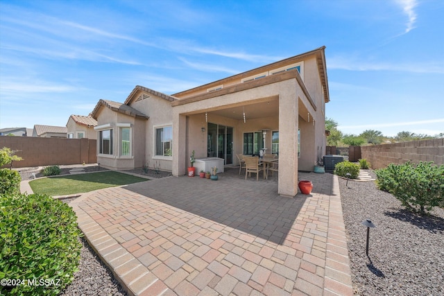 rear view of house featuring central AC unit, a fenced backyard, a tile roof, a patio area, and stucco siding