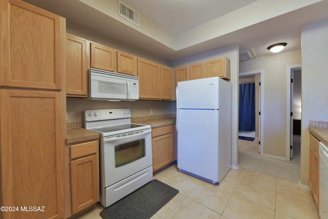 kitchen with white appliances, light brown cabinets, and light tile patterned floors