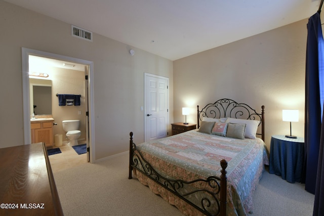 carpeted bedroom featuring sink and ensuite bath