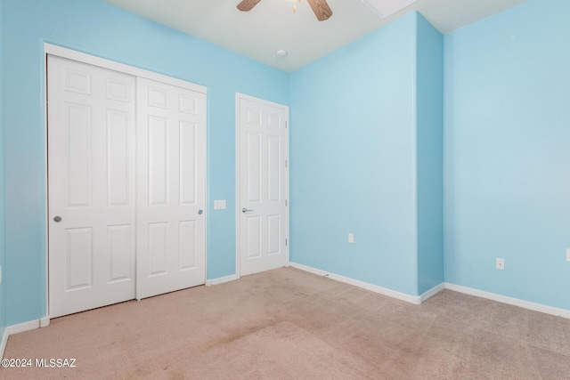 unfurnished bedroom with ceiling fan, a closet, and light carpet