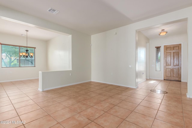 tiled spare room with a notable chandelier and a wealth of natural light