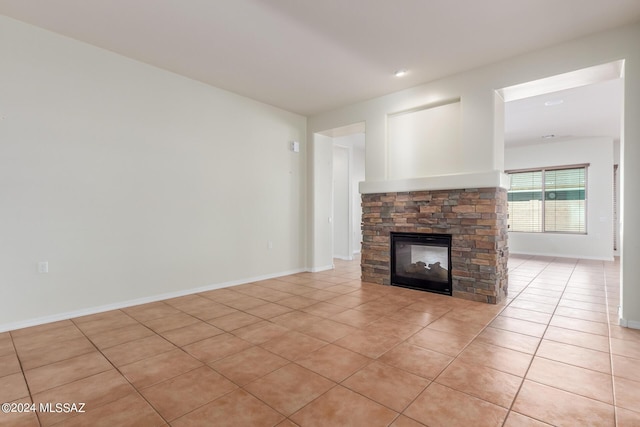 unfurnished living room with light tile patterned flooring and a stone fireplace