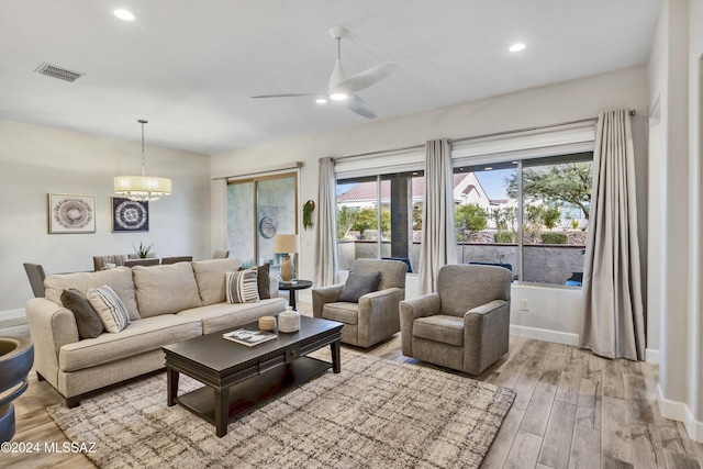 living room with light hardwood / wood-style flooring and ceiling fan with notable chandelier