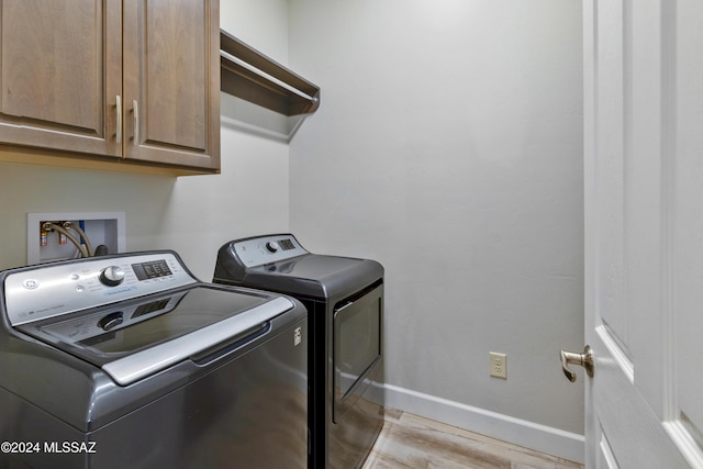 laundry area with independent washer and dryer, cabinets, and light wood-type flooring