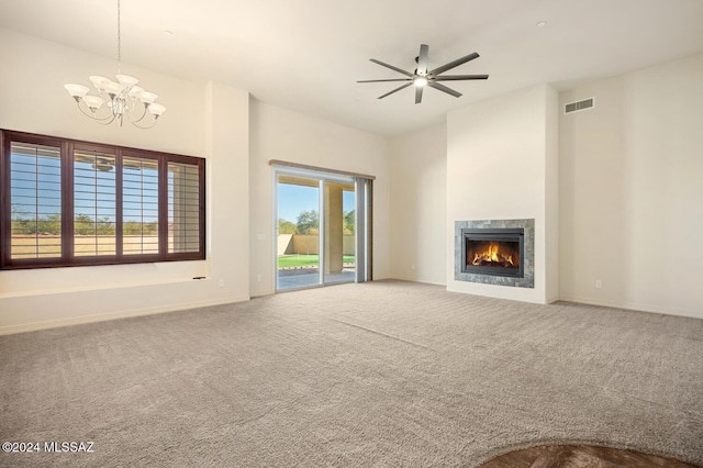 unfurnished living room featuring carpet flooring, a towering ceiling, and ceiling fan with notable chandelier