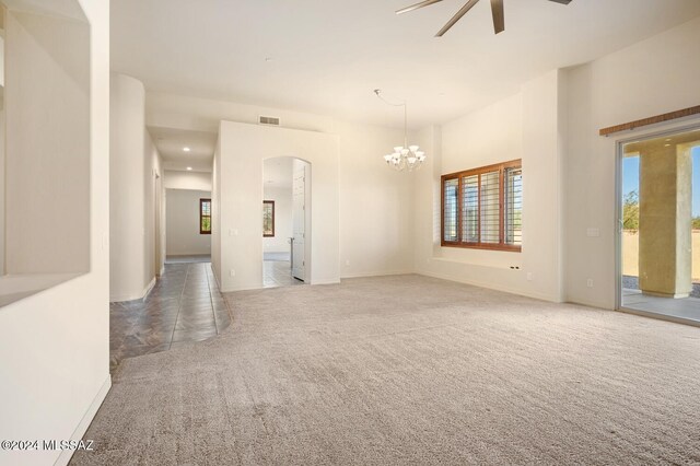 carpeted empty room featuring ceiling fan with notable chandelier