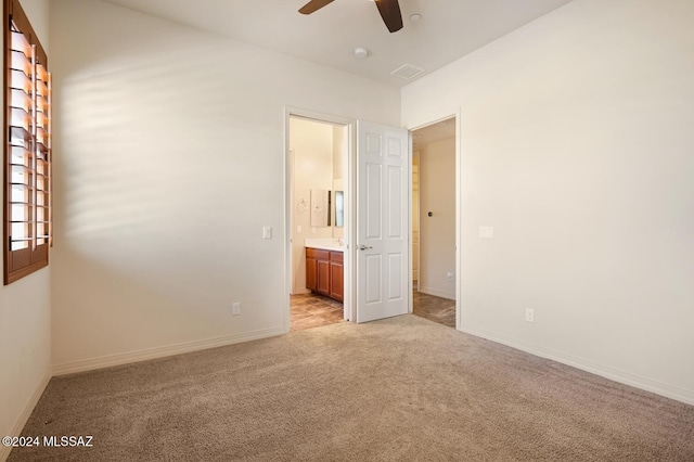 unfurnished bedroom featuring light colored carpet, ceiling fan, and ensuite bathroom