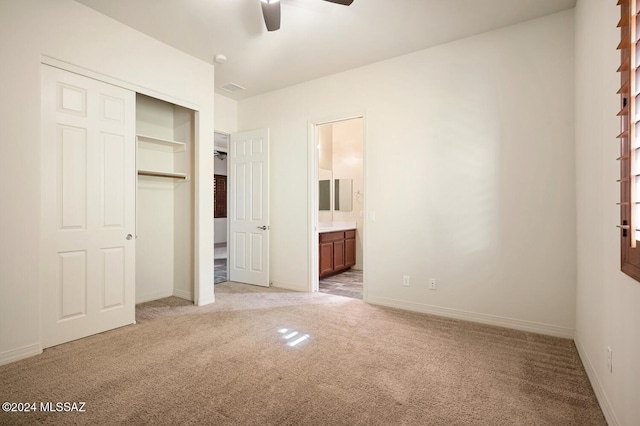 unfurnished bedroom featuring a closet, light colored carpet, ceiling fan, and ensuite bathroom