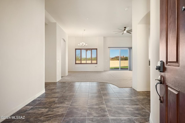 foyer entrance with dark carpet and ceiling fan with notable chandelier