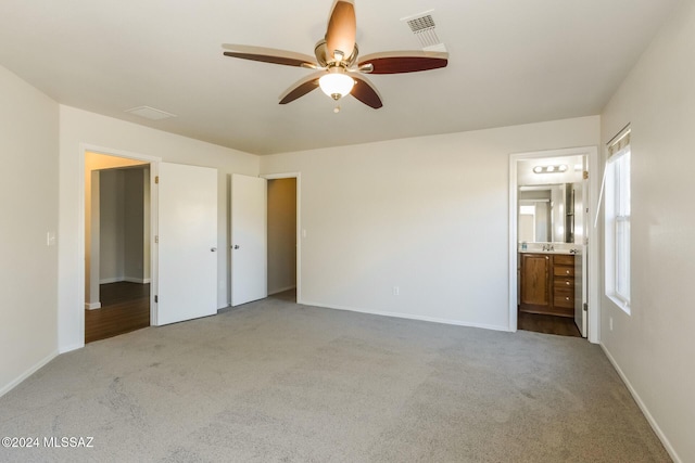 unfurnished bedroom with light carpet, connected bathroom, and ceiling fan