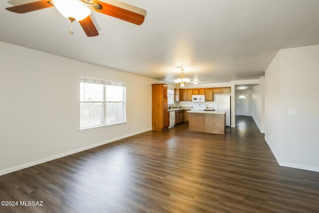 unfurnished living room with ceiling fan with notable chandelier and dark wood-type flooring