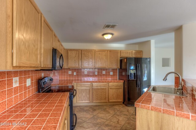 kitchen featuring black appliances, tasteful backsplash, tile countertops, and sink