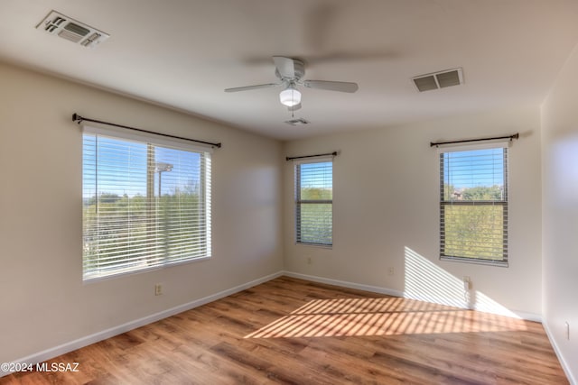 spare room featuring a healthy amount of sunlight, ceiling fan, and light hardwood / wood-style floors