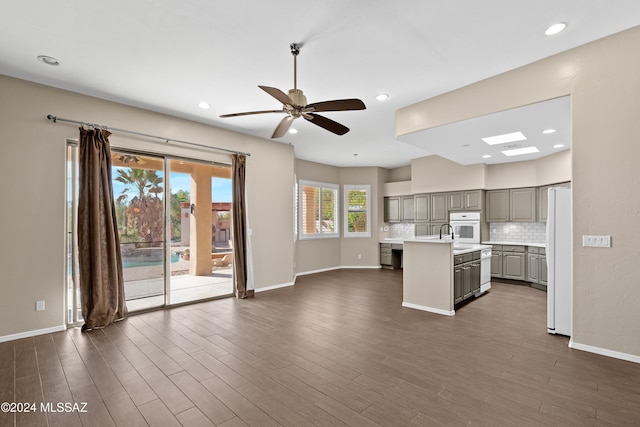 kitchen featuring gray cabinetry, ceiling fan, dark hardwood / wood-style flooring, an island with sink, and white appliances