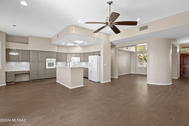 kitchen featuring white appliances, dark wood-type flooring, gray cabinets, a kitchen island, and hanging light fixtures