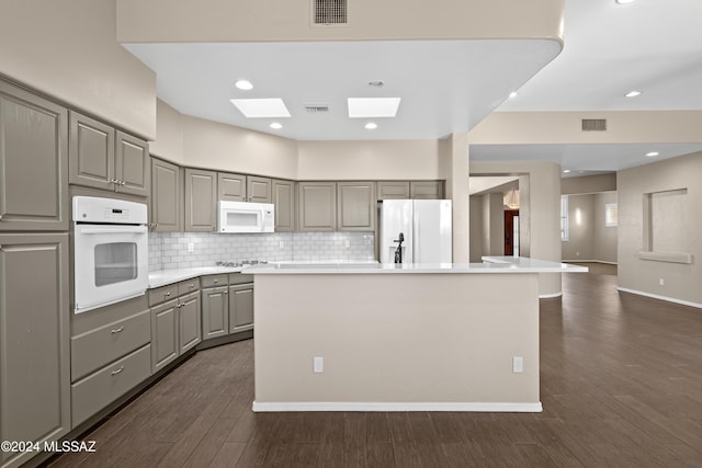 kitchen featuring white appliances, a center island, gray cabinets, and dark hardwood / wood-style floors