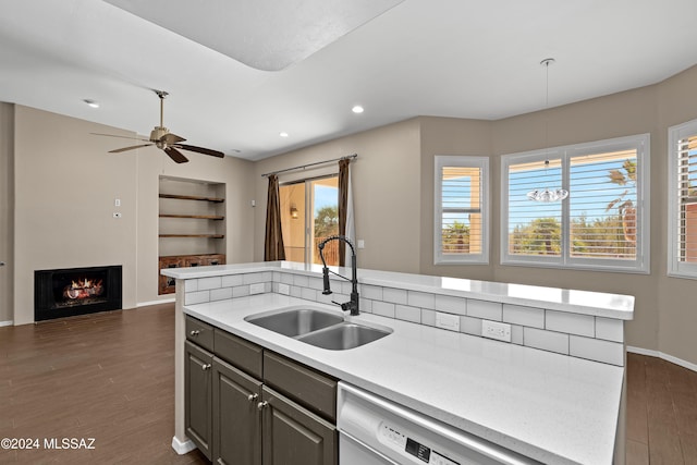 kitchen featuring sink, dark wood-type flooring, stainless steel dishwasher, an island with sink, and decorative light fixtures