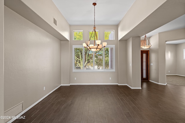 spare room with dark hardwood / wood-style flooring and an inviting chandelier