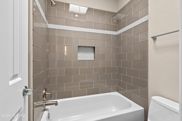 bathroom with toilet and tiled shower / bath