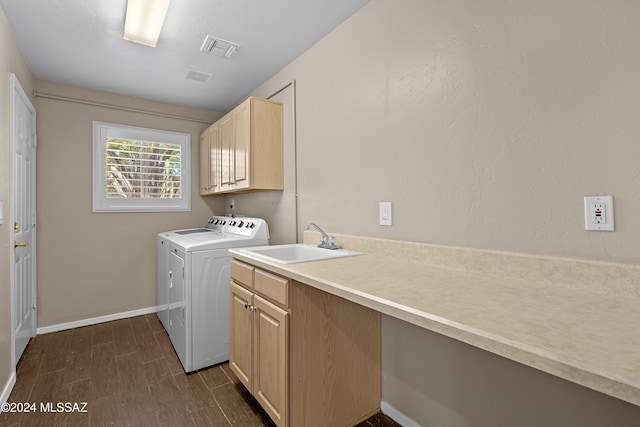 laundry room with washing machine and clothes dryer, dark wood-type flooring, cabinets, and sink