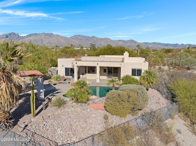 back of property with a mountain view, a patio area, and a fenced in pool