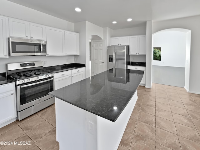 kitchen with dark stone countertops, a center island, white cabinets, and stainless steel appliances