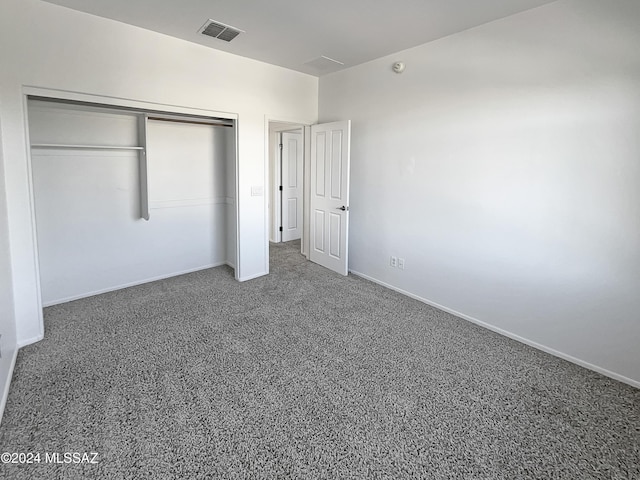 unfurnished bedroom with dark carpet and a closet