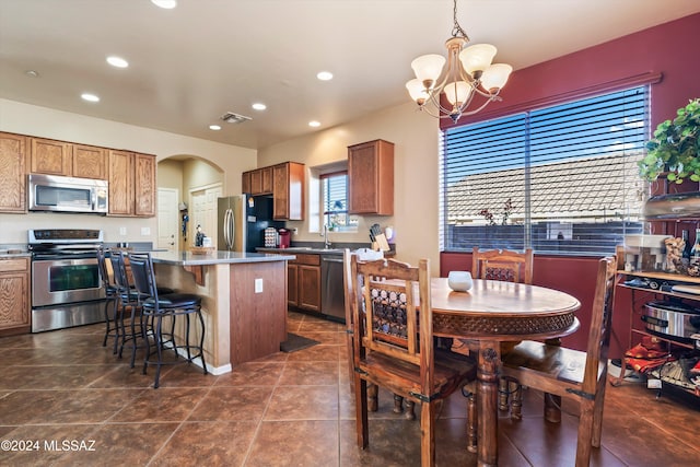 kitchen with a breakfast bar, stainless steel appliances, pendant lighting, a chandelier, and a center island