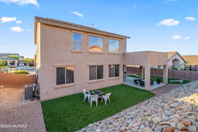 rear view of property featuring outdoor lounge area, cooling unit, a patio area, and a lawn