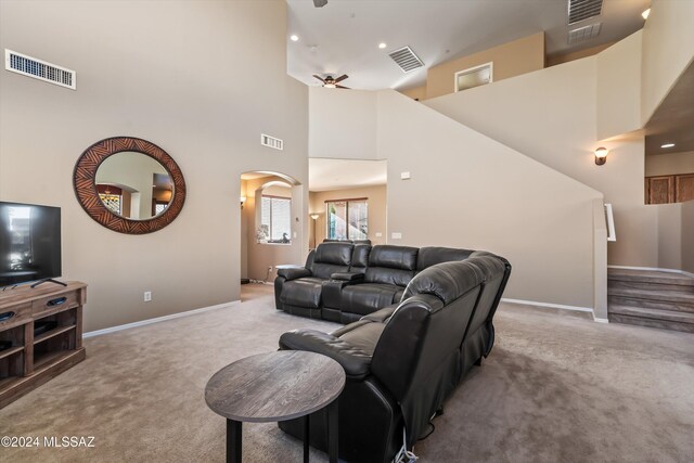 living room with light carpet, a towering ceiling, and ceiling fan