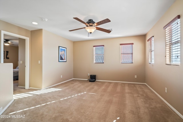 spare room with ceiling fan and light colored carpet