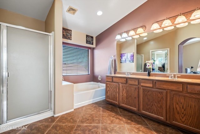 bathroom with tile patterned floors, vanity, separate shower and tub, and vaulted ceiling