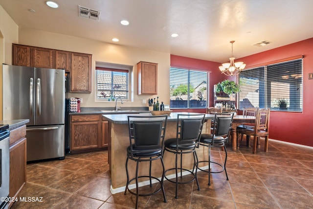 kitchen featuring stainless steel appliances, sink, decorative light fixtures, an inviting chandelier, and a kitchen island