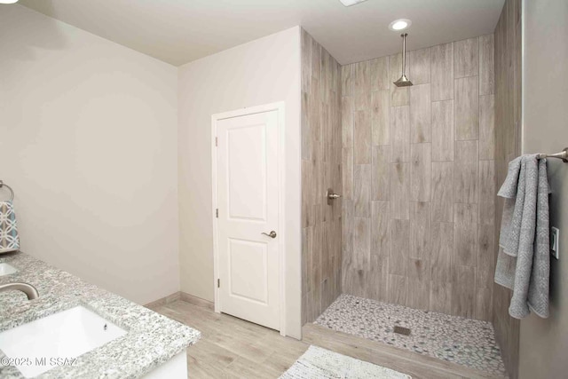 bathroom featuring tiled shower, vanity, and hardwood / wood-style floors