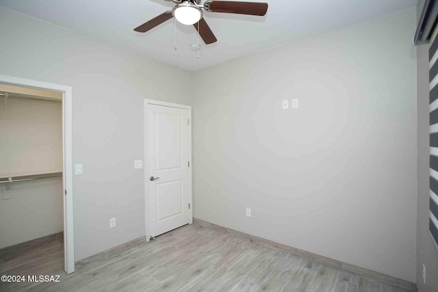 unfurnished bedroom featuring ceiling fan, a closet, and light wood-type flooring