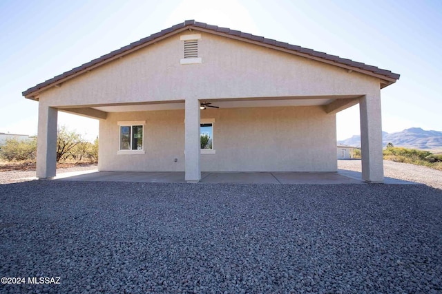 back of property featuring a mountain view, ceiling fan, and a patio area