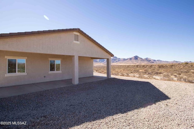 view of side of property with a mountain view and a patio area