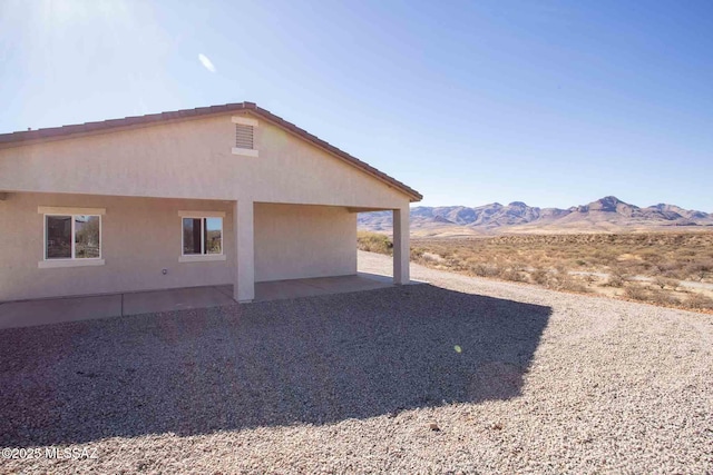 view of side of home with a mountain view and a patio area