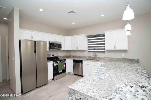 kitchen with stainless steel appliances, sink, pendant lighting, and white cabinets