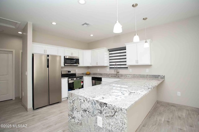 kitchen with appliances with stainless steel finishes, light wood-type flooring, hanging light fixtures, and white cabinets