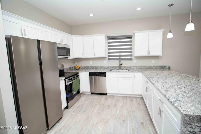 kitchen with sink, white cabinetry, stainless steel appliances, decorative light fixtures, and kitchen peninsula