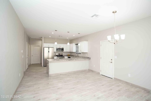 kitchen featuring appliances with stainless steel finishes, white cabinetry, hanging light fixtures, light hardwood / wood-style floors, and kitchen peninsula