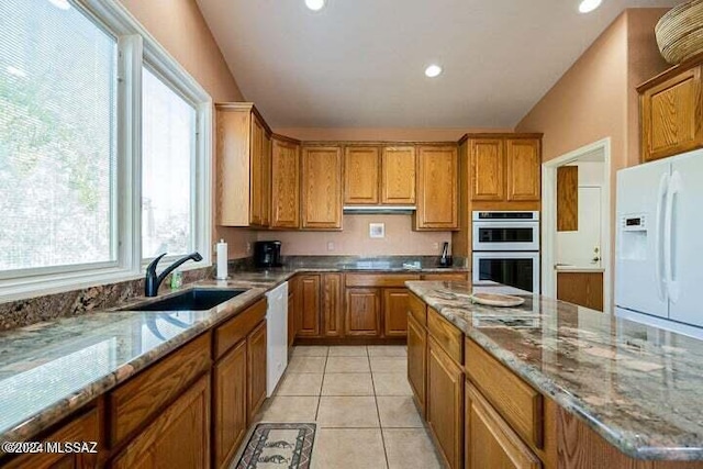 kitchen with brown cabinets, light tile patterned floors, lofted ceiling, a sink, and white appliances