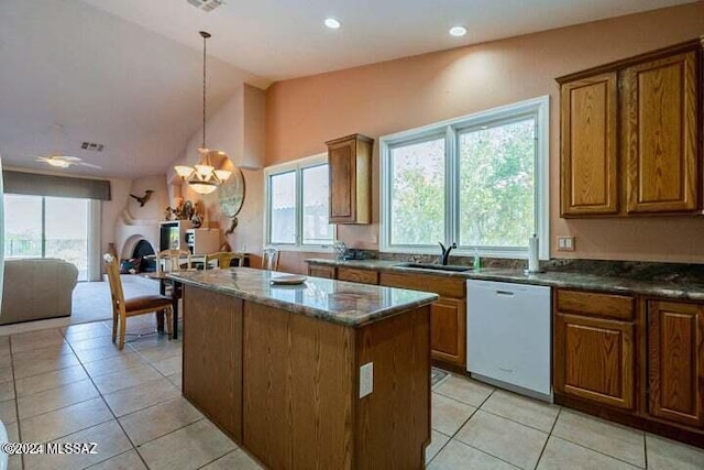 kitchen with a center island, brown cabinets, a healthy amount of sunlight, white dishwasher, and a sink