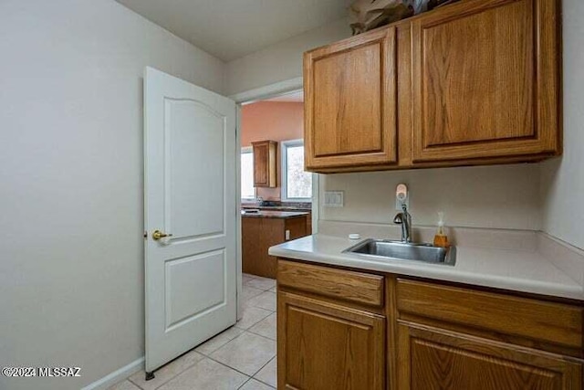 kitchen with light tile patterned floors, light countertops, a sink, and brown cabinets