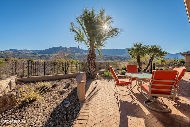 view of patio featuring outdoor dining area, a mountain view, and fence