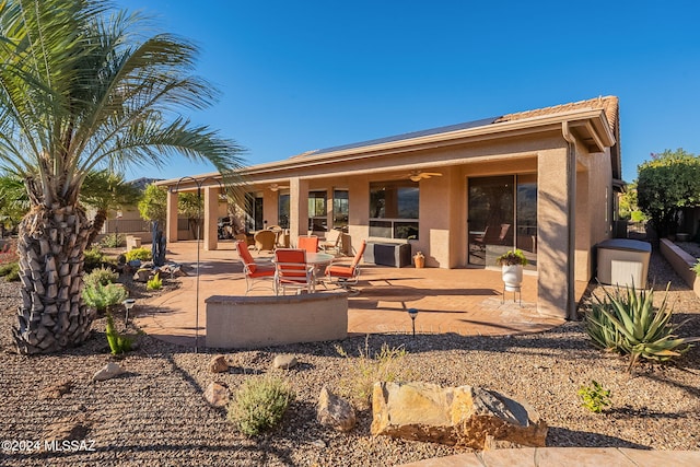 rear view of property with a patio area, ceiling fan, solar panels, and stucco siding