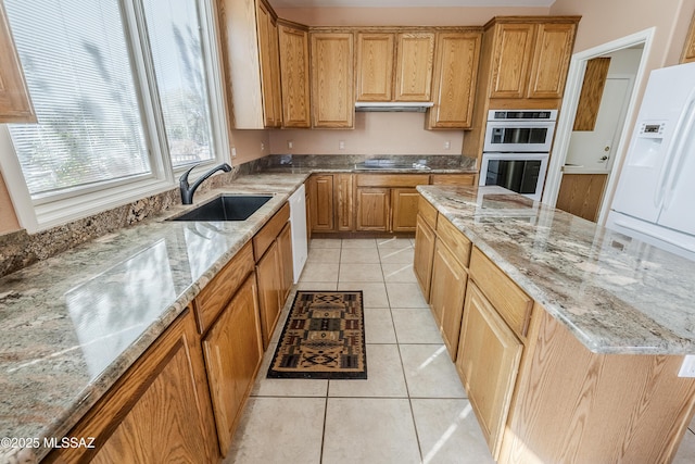 kitchen with light tile patterned floors, black electric stovetop, double wall oven, a sink, and light stone countertops
