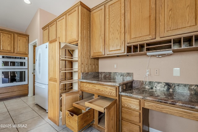 kitchen featuring open shelves, light tile patterned floors, stainless steel double oven, freestanding refrigerator, and dark stone countertops